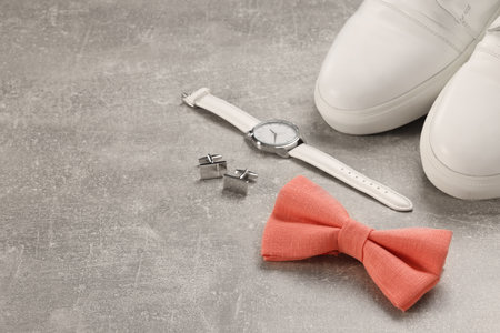 Stylish pink bow tie, wrist watch, shoes and cufflinks on light gray background, space for textの写真素材