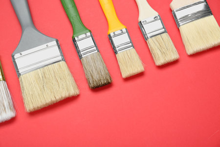 Many different paint brushes on red background, flat lay. Space for textの写真素材