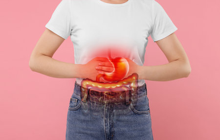 Woman suffering from stomach ache on pink background, closeup. Illustration of unhealthy gastrointestinal tractの写真素材