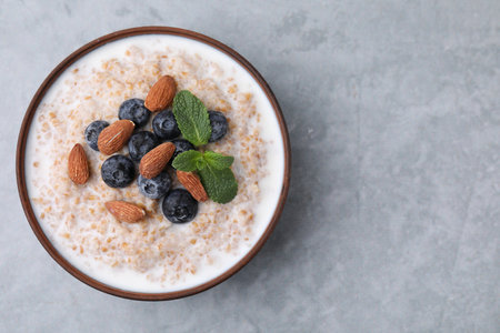 Tasty wheat porridge with milk, blueberries and almonds in bowl on gray table, top view. Space for textの写真素材