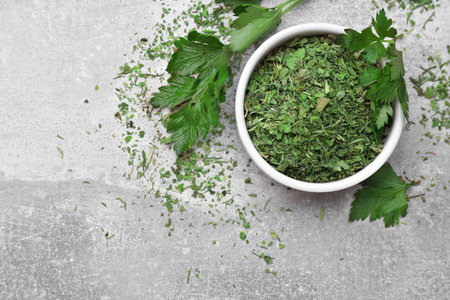 Dried parsley and fresh leaves on light gray table, flat lay. Space for textの写真素材