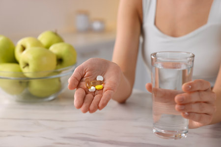 Woman with glass of water and pills at table indoors, closeup. Weight lossの写真素材