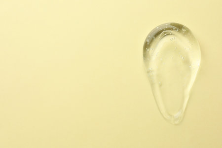 Clear cosmetic gel on yellow background, top view. Space for text