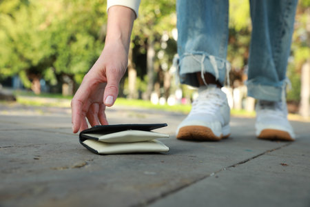 Woman picking up white leather purse outdoors, closeup. Lost and foundの写真素材