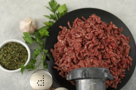 Mining beef with meat grinder. Parsley, garlic and spices on gray table, flat layの写真素材