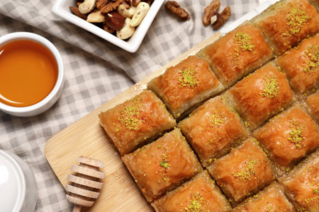 Delicious sweet baklava with nuts and honey on table, flat layの写真素材