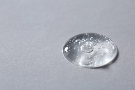 Drop of cosmetic serum on light background, macro view. Space for textの写真素材