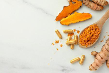 Aromatic turmeric powder, pills and raw roots on white marble table, flat lay. Space for textの写真素材
