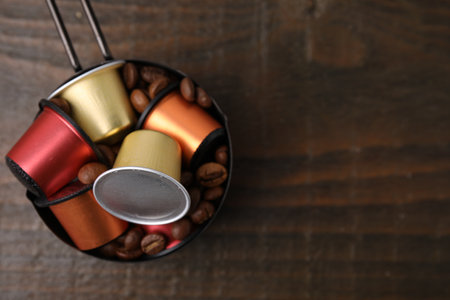 Saucepan with coffee capsules and beans on wooden table, top view. Space for textの写真素材