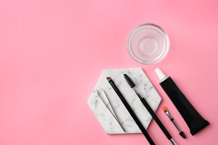 Flat lay composition with eyebrow henna and tools on pink background. Space for textの写真素材