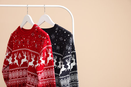 Rack with Christmas sweaters on beige background, space for textの写真素材