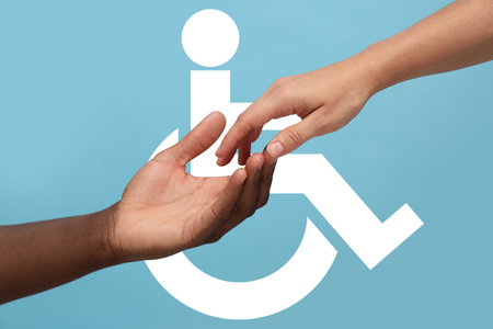 Inclusion concept. Man offering hand woman against international symbol of access on light blue background, closeupの写真素材