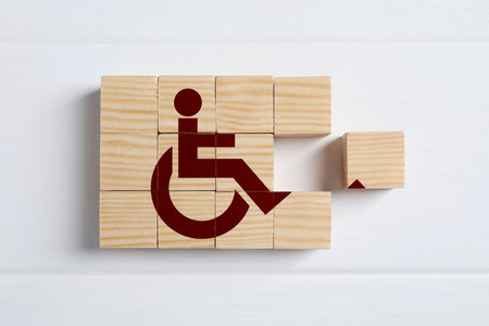 Inclusion concept. Making international symbol of access with wooden cubes on white background, top viewの写真素材