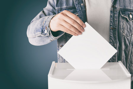 Man putting his vote into ballot box on gradient color background, closeupの写真素材