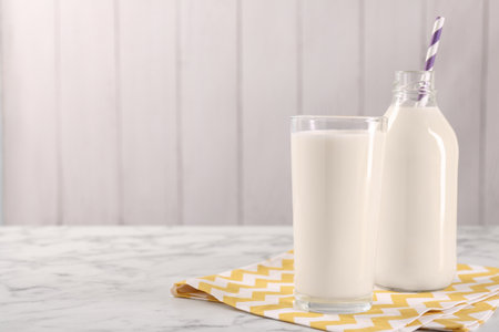 Glassware with tasty milk on white marble table, space for textの写真素材