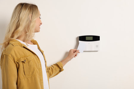 Home security system. Woman using key card indoors