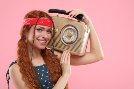 Stylish young hippie woman with retro radio receiver on pink backgroundの写真素材