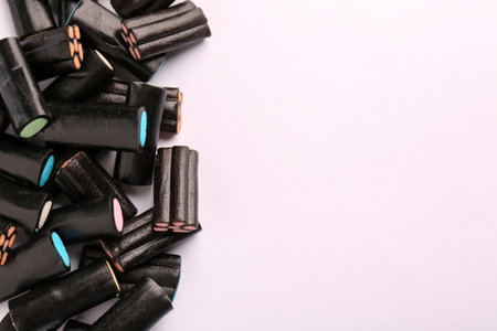 Tasty liquorice candies on light background, top view. Space for text