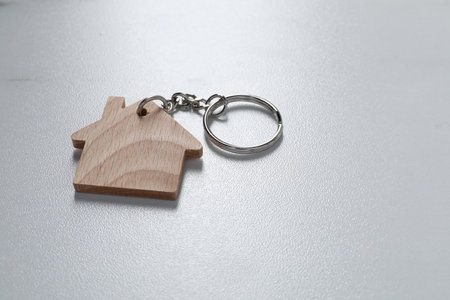 Wooden keychain in shape of house on light table, closeup. Space for textの写真素材