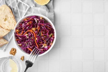 Tasty salad with red cabbage and walnuts on white tiled table, flat lay. Space for textの写真素材