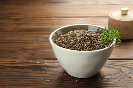 Bowl of dry seeds and fresh dill on wooden table, closeup. Space for textの写真素材
