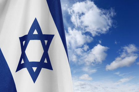 National flag of Israel against blue sky with clouds