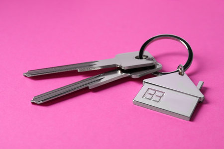 Keys with keychain in shape of house on pink background, closeupの写真素材