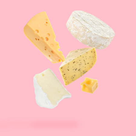 Different kinds of cheese falling on pink backgroundの写真素材