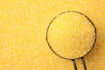 Scoop on raw corn grits, top view. Space for text