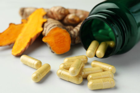 Turmeric roots, pills and bottle on white table, closeupの写真素材