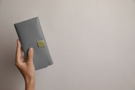 Woman holding gray leather purse on light background, closeup. Space for textの写真素材