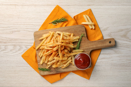 Delicious French fries served with sauce on white wooden table, flat lay