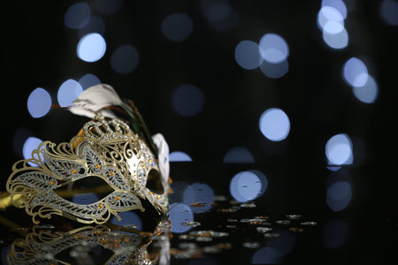 Beautiful carnival mask on table against blurred lights. Space for textの写真素材