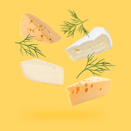 Different kinds of cheese falling on golden backgroundの写真素材