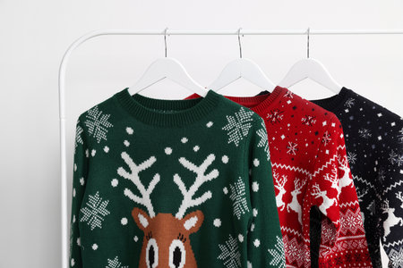 Rack with different Christmas sweaters on white backgroundの写真素材