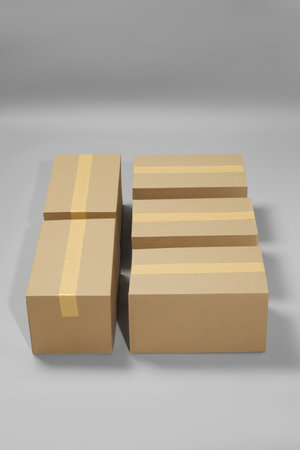Many closed cardboard boxes with tape on light gray backgroundの写真素材
