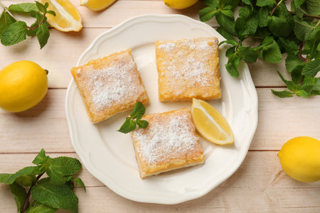 Tasty lemon bars with powdered sugar and mint on wooden table, flat layの写真素材