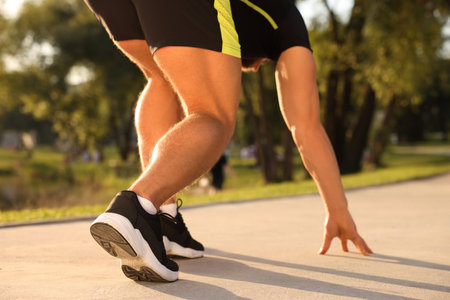 Runner on starting position in park on sunny day, closeup