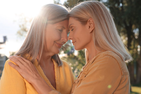 Family portrait of happy mother and daughter spending time together outdoors on sunny dayの写真素材