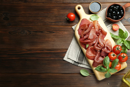 Board with delicious bresaola and other snacks served on wooden table, flat lay. Space for textの写真素材