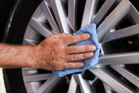 Man cleaning car wheel with rag, closeupの写真素材