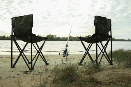 Folding chairs and fishing rod at riversideの写真素材