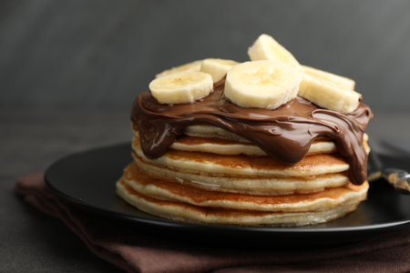 Tasty pancakes with chocolate spread and sliced banana on table against gray background, closeupの写真素材