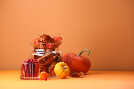 Composition with beautiful autumn leaves, berries and pumpkins on table against orange background, space for textの写真素材