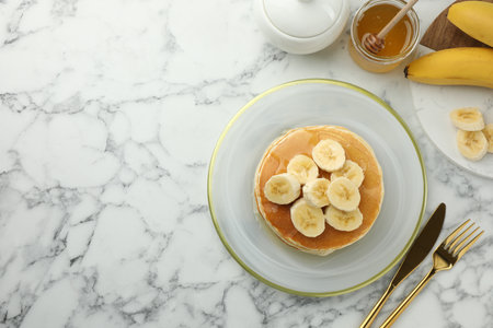 Delicious pancakes with bananas and honey served on white marble table, flat lay. Space for textの写真素材