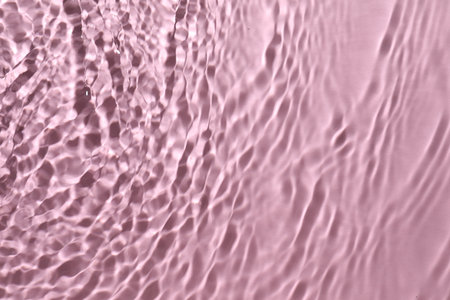 Rippled surface of clear water on pink background, top viewの写真素材