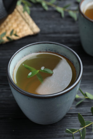 Cup of aromatic eucalyptus tea on black wooden table, closeupの写真素材