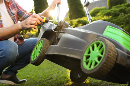 Man with screwdriver fixing lawn mower in garden, closeupの写真素材