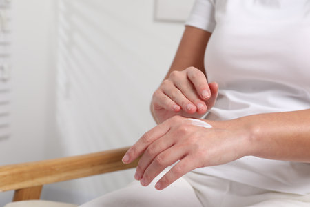 Woman applying cosmetic cream onto hand on blurred background, closeup. Space for textの写真素材