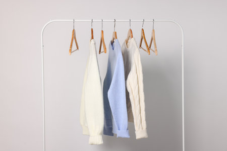 Rack with different warm sweaters on light backgroundの写真素材